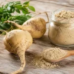 Raiz e pó de maca peruana em superfície de madeira rústica com folhas verdes ao fundo